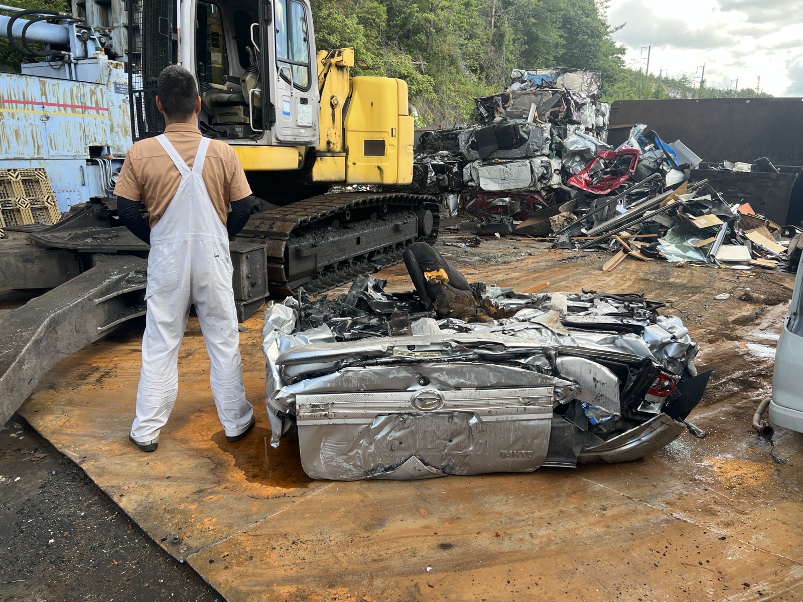 解体を終え、四角く潰れた車を見つめる当社スタッフ